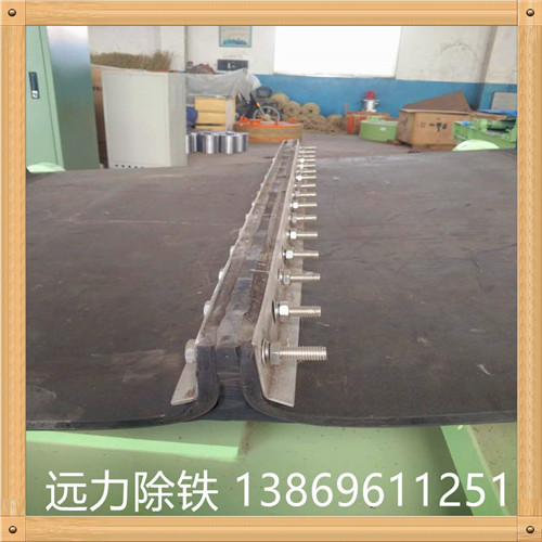 橡膠除鐵器皮帶 除鐵器環形帶接頭方法有三種：   　　(1)直接硫化成環形帶子.  　　(2)硫化時留生頭 除鐵器環形帶生產商,使用時根據要求現場加熱加壓使接頭部分硫化.  　　(3)用膠黏劑現場黏合.由于無機械接頭,運行平穩,適用于選礦,化肥等部門的物料輸送.  　　除鐵器環形輸送帶是指平型輸送帶生產完成后,因為使用的環境或者條件限制,必須使用環形輸送帶時,我們會對平型輸送帶進行硫化接頭(又稱熱粘),使其變為環形輸送帶.其帶芯接頭處強力可達到膠帶本體強力的90%,膠帶表面無明顯接頭缺陷.     因此 除鐵器環形帶的求購,環形輸送帶運輸平衡,使用伸長小.環形輸送帶帶芯用優質全棉或維棉交織帆布制成,一般2-8層或用尼龍帆布(或聚酯帆布)作強力層.